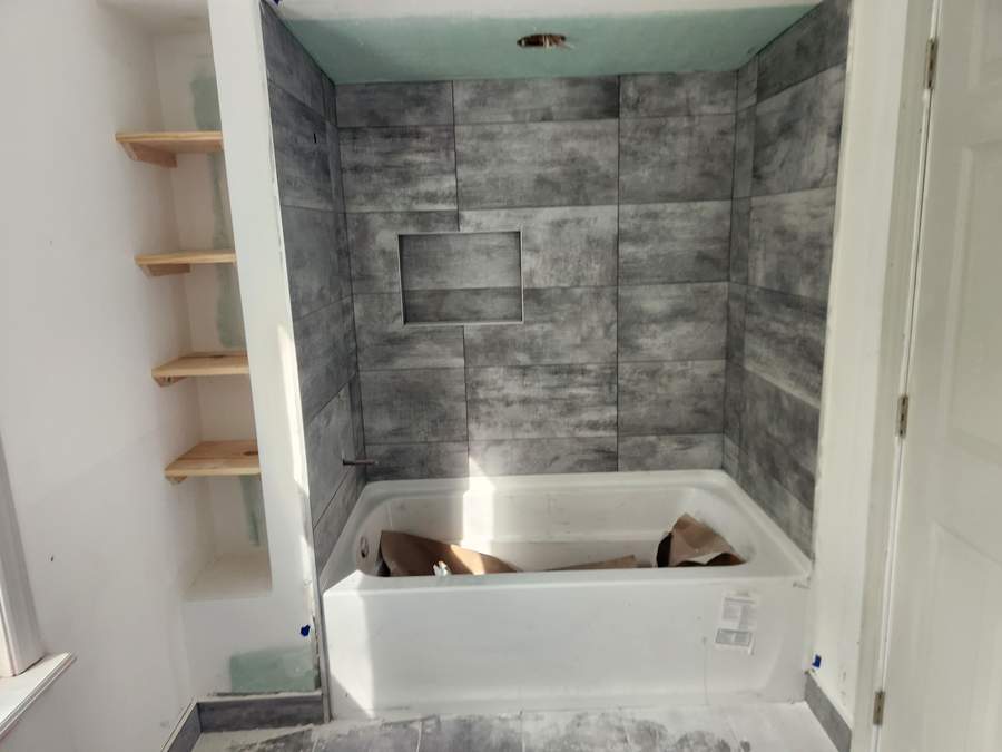 Tub surround in grey tile with built-in shelves